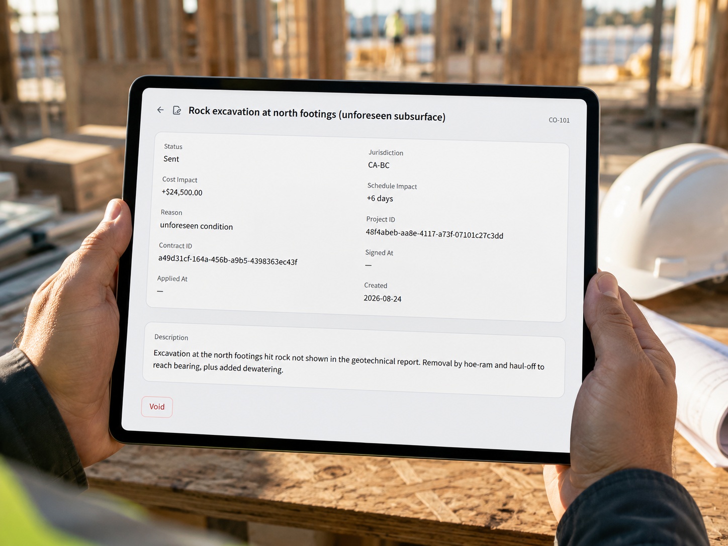 A general contractor in a hard hat on an active construction site holding a tablet that shows a CrewOS change order with its cost impact, schedule impact, and signature status